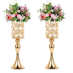 two gold vases with flowers on them sitting side by side in front of each other