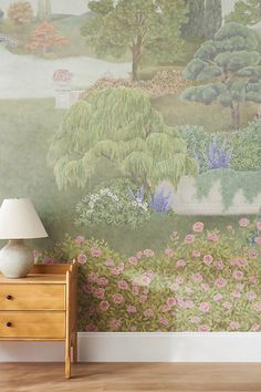 a room with a lamp, dresser and painting on the wall behind it is a garden scene