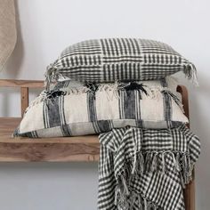 two pillows sitting on top of a wooden bench next to a pillow with tassels