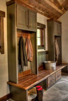 a wooden bench sitting inside of a room next to a wall mounted coat dryer