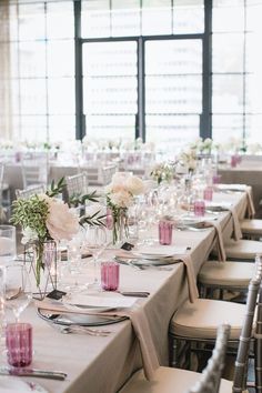 the tables are set with white and pink centerpieces, silverware, and candles