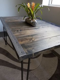 a wooden table with metal legs and a potted plant sitting on top of it