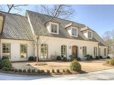 a large white house with lots of windows and bushes in front of the home's driveway