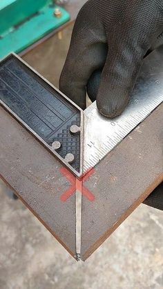 a person holding a metal object with a ruler on it's side and another hand in the background