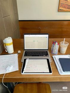 an open laptop computer sitting on top of a wooden desk next to a cup of coffee