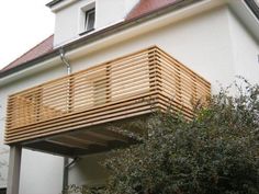 a wooden balcony on the side of a white house