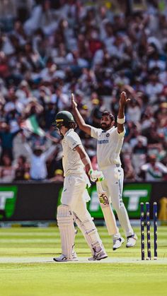 two cricket players high fiving each other in front of an audience at a stadium