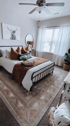 a bedroom with a large bed, ceiling fan and two pictures on the wall above it