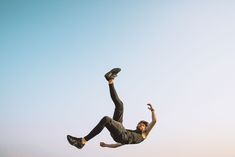 a man flying through the air while riding on top of a skateboard in front of a blue sky