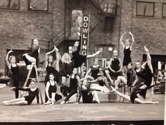 black and white photograph of dancers in front of a brick building with their arms up