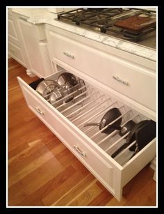 an open drawer in the middle of a kitchen with pots and pans on it