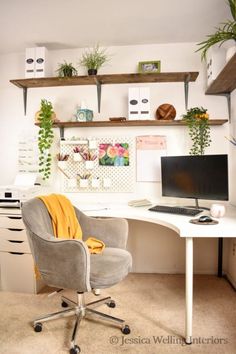 a desk with a chair, computer monitor and plants on the shelves above it in a home office