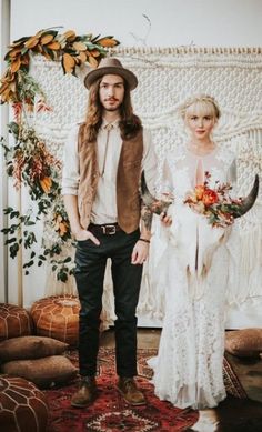 a man and woman standing next to each other in front of a wall with flowers