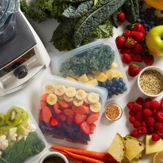 various fruits and vegetables are in plastic containers on a counter top next to a blender