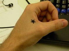 a person with a small star tattoo on their left hand next to a computer keyboard