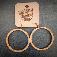 pair of wooden hoop earrings with logo on the front and back of each earring