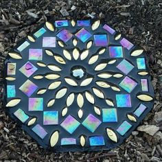 a black and gold mosaic design is on the ground in front of some wood chips