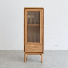 a wooden cabinet sitting on top of a floor next to a white wall in an empty room