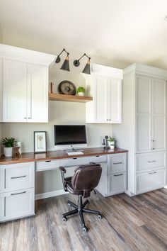 a home office with white cabinets and wood flooring