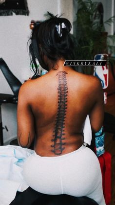 the back of a woman's body with a skeleton tattoo on her lower back