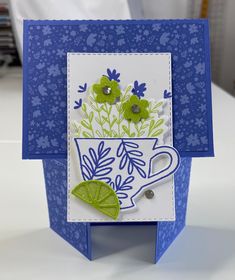 a close up of a card on a table with a cup and flowers in it