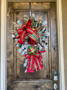 a christmas wreath on the front door of a house decorated with red and green ribbons