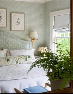 a bedroom with green wallpaper and white bedspread in front of a window