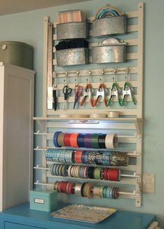 an organized craft room with blue drawers and white shelving unit filled with spools of thread