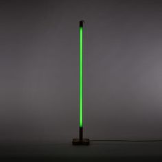 a green light is shining on the floor next to a black pole with a cord