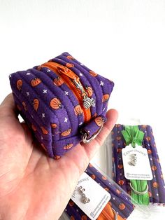 a hand holding a small purple bag with pumpkins on it