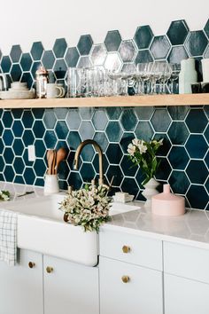 a kitchen sink with wooden utensils and dishes on the shelf above it in front of a blue tiled backsplash