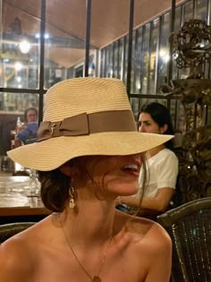 a woman sitting at a table wearing a hat