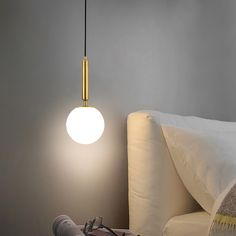 a light that is on above a bed in a room with white sheets and pillows