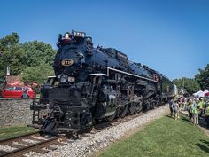 an old fashioned steam engine is on display at the train museum, with people standing around it