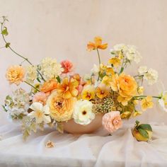 a vase filled with lots of flowers on top of a white cloth covered tablecloth