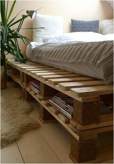 a bed made out of wooden pallets with a plant in the corner next to it