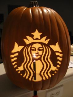 a pumpkin shaped like a starbucks logo with a lit candle in the shape of a woman's face