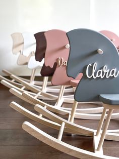 a row of rocking chairs with the name clara written on them in white and pink