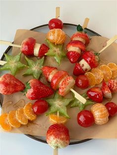 strawberries and oranges are arranged on skewers