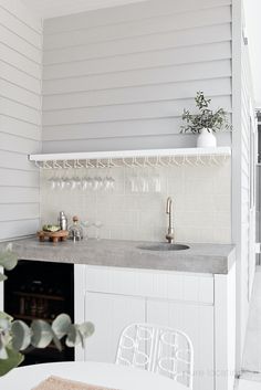 a white kitchen with a sink, stove and counter top next to a dining room table