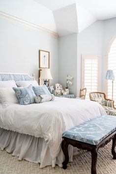 a white bed sitting in a bedroom next to two windows