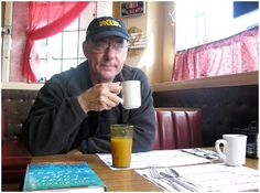 an older man sitting at a table with a glass of orange juice