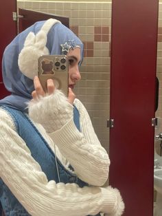 a woman taking a selfie in the bathroom wearing a blue and white outfit while holding a cell phone