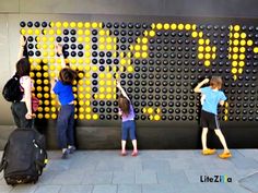 three children are standing in front of a wall made out of yellow and black circles