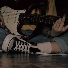 a person sitting on the floor with their feet up while playing an electric bass guitar