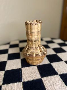 a small vase sitting on top of a checkered tablecloth covered table with black and white squares