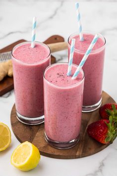 two glasses filled with pink smoothie next to sliced lemons