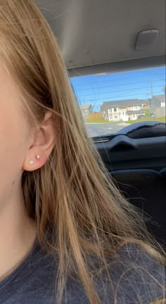 a girl with ear piercings in the back seat of a car