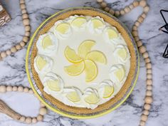 a lemon pie with white frosting and sliced lemons on the top, surrounded by wooden beads