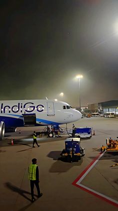 an airplane on the tarmac at night with people standing around and looking at it